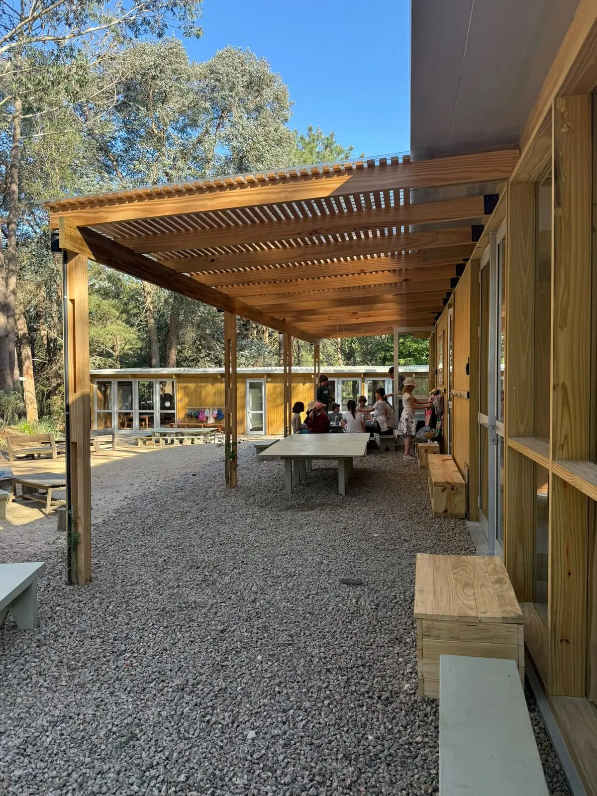 Galería con pérgola de madera junto al patio · Portal Bosque, La Barra, Uruguay